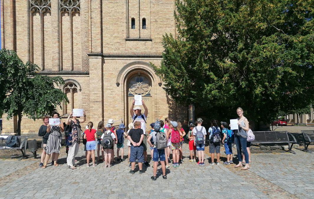 Auf dem Bild sind Kinder vor dem Eingang zur Fürstenberger Stadtkirche zu sehen.